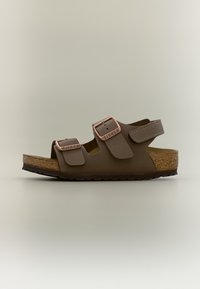 Καφέ σανδάλι Birkenstock με δύο ρυθμιζόμενες χάλκινες αγκράφες και σόλα από φελλό σε ουδέτερο φόντο.