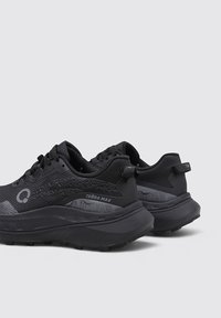 Zapatillas deportivas negras con una parte superior de malla texturizada, que cuentan con una suela de goma gruesa, acentos con patrón y una pestaña en el talón.