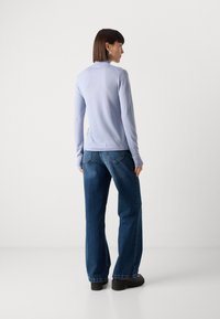 Light blue long-sleeve top with a simple design, paired with high-waisted dark blue wide-leg jeans and black platform shoes.