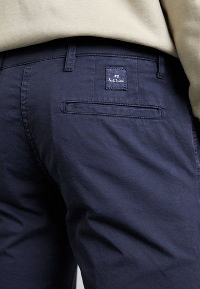 Marineblå bomullsbukser med en jevn tekstur, med en baklomme og et merke med "PS Paul Smith" brodert i hvitt.