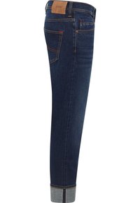 Dunkelblaue Denim-Jeans mit schmaler Passform, Kontrastnähten, Lederpatch am Bund und umgeschlagenen Bündchen, die ein helleres Innenfutter zeigen.