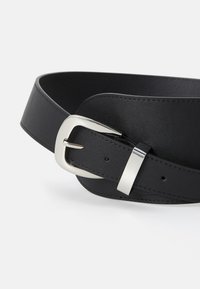 Černý kožený opasek se stříbrnou kovovou přezkou. Má hladký povrch a klasický design s předpřenášenými otvory pro nastavení.