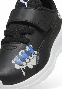 Baskets synthétiques noires avec semelle blanche, présentant un graphique 'BMW Motorsport' en bleu, un dessus texturé et des lacets noirs.