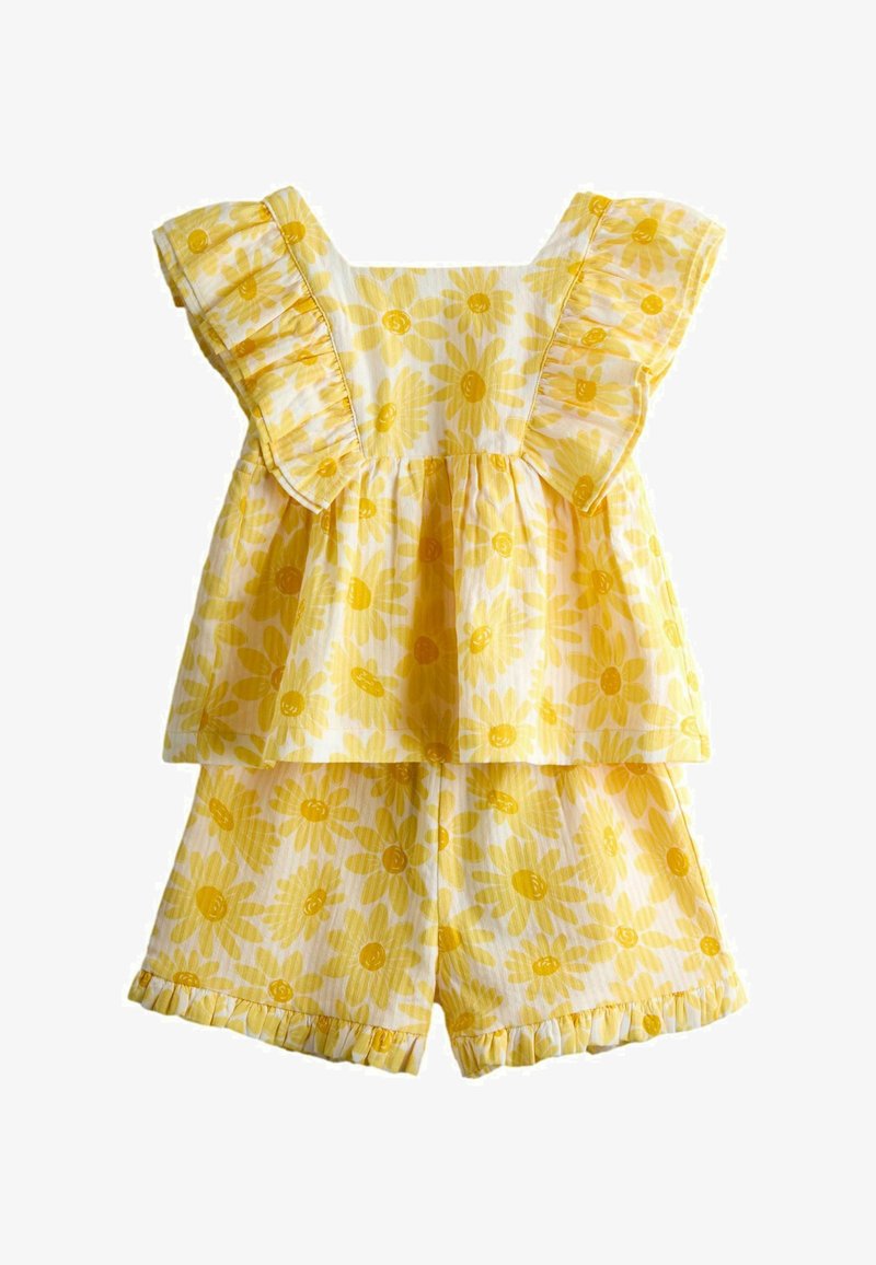 Top galben fără mâneci cu imprimeu floral, cu volane la umeri, și pantaloni scurți asortați cu volane, pentru copii, pe fundal alb.