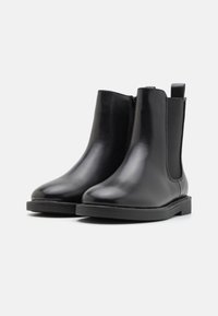 Czarne skórzane botki za kostkę o gładkim wykończeniu, okrągłym nosku, elastycznych bocznych panelach oraz pętelce z tyłu dla łatwego zakładania.