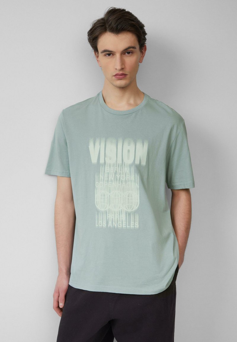 Lichtgroene katoenen t-shirt met een ronde hals en korte mouwen. Bevat gedurfde witte tekst met stadnamen en grafische designelementen.