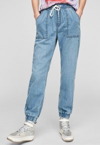 Pantalones jogger azul claro con cinturilla elástica y bolsillos, que presentan un corte holgado, puños acanalados y detalles de costura visibles.