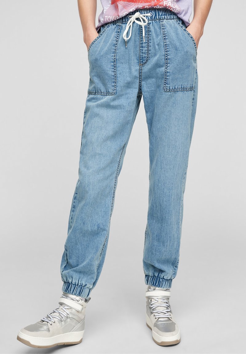 Pantalones jogger azul claro con cinturilla elástica y bolsillos, que presentan un corte holgado, puños acanalados y detalles de costura visibles.