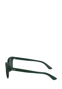 Grønne plast solbriller med vinklede rammer og slanke stenger. Har en kontrastlogo på siden. Gjennomsiktige linser.