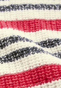 Randig textil med växlade band av röd, vit och marinblå, med ett strukturerat stickmönster som ger djup och dimension.