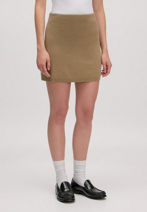 Gebreide minirok in olijfgroen met een aansluitend ontwerp, geribbelde tailleband en een gladde textuur. Gekocht met witte sokken en zwarte loafers.