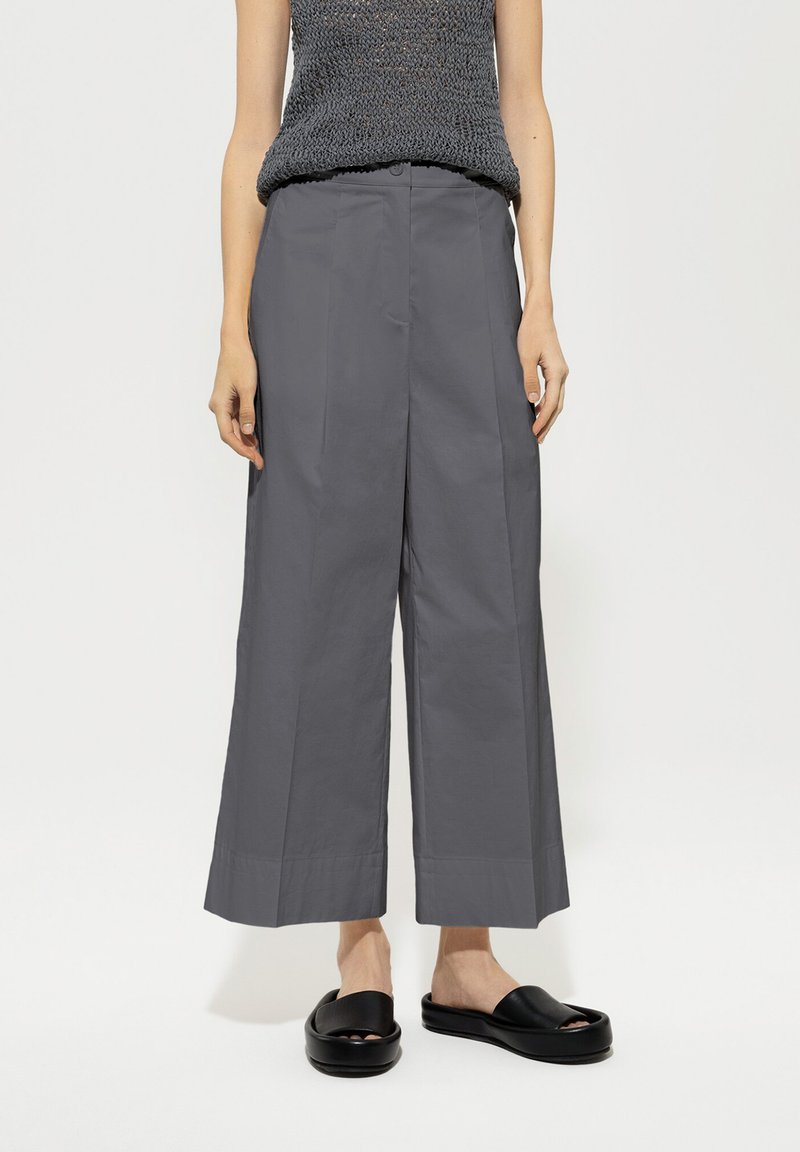 Gray wide-leg trousers with a smooth texture, featuring a high waist and two front pockets; paired with black slip-on sandals.