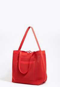 Rode netten tas met dubbele handgrepen, grote hoofdcompartiment en een voorkant zak. Heeft een gestructureerd, open ontwerp met textuurstof.