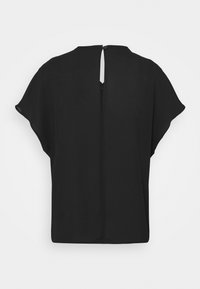 Blouse noire à manches courtes avec un col rond, une ouverture en goutte d'eau au dos fermée par un bouton, et une silhouette ample et fluide.