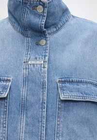 Hellblaue Jeansjacke mit hohem Kragen, Metall-Druckknöpfen, zwei aufgesetzten Brusttaschen und einem kleinen weißen "Marc O'Polo Denim" Etikett.