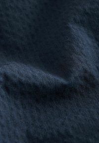 Tumši zilas krāsas audums ar faktūru, kas ietver smalkus, dažādus rakstus un gludu kritumu. Ideāli tekstilmateriāliem un mēbelēm.