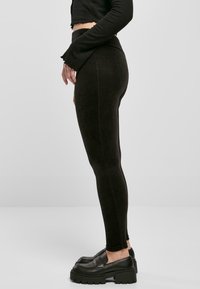 Czarne prążkowane legginsy z wysokim stanem i bezszwowym wykończeniem, z dopasowanym krojem i gładką fakturą. Noszone z masywnymi czarnymi loafersami.