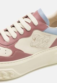 Zapatilla de cuero con diseño de corte bajo, que presenta acentos en rosa, crema y azul claro, cordones gruesos blancos y suela texturizada para mayor agarre.