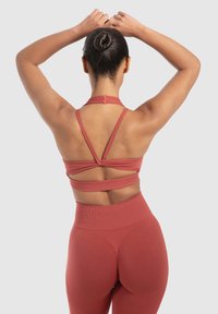 Roodbruin sportBH met meerdere banden, een gladde textuur en uitsparingen op de rug, gecombineerd met hoge taille legging.