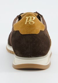 Baskets en suède marron avec un accent de talon beige et un logo doré. Présentent une semelle intermédiaire blanche et une semelle extérieure en caoutchouc texturé marron.