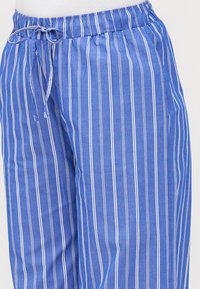 Blue striped pants with an elastic waistband, featuring white and thin multicolored stripes. Material appears lightweight with a smooth texture.