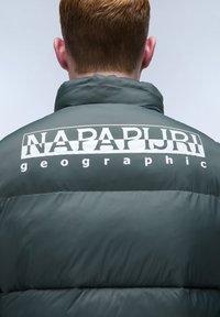 Grön puffjacka med hög krage, horisontell quiltad mönstring och en vit logotyp på baksidan med texten "NAPAPIJRI geographic."