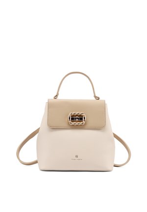 Borsa beige e crema con manico superiore, fibbia decorativa intrecciata sulla patta e sottili tracolle su sfondo bianco.