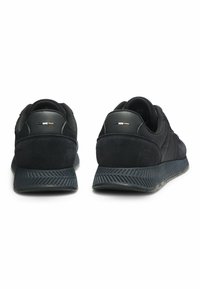Baskets de sport noires avec une tige en daim texturé et en maille, dotées d'une semelle en caoutchouc à nervures et d'un minimum de branding à l'arrière.