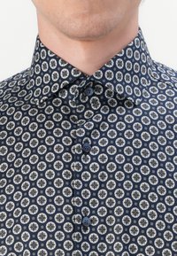 Navy blue button-up shirt with a floral pattern in cream and black, featuring a spread collar and dark blue buttons.