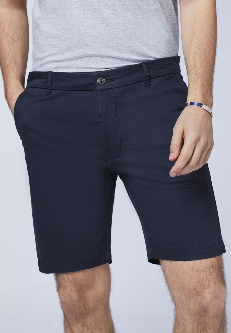 Marineblaue Shorts aus glattem Stoff, mit Knopfverschluss, Gürtelschlaufen und Seitentaschen. Umgeschlagen auf Kniehöhe.