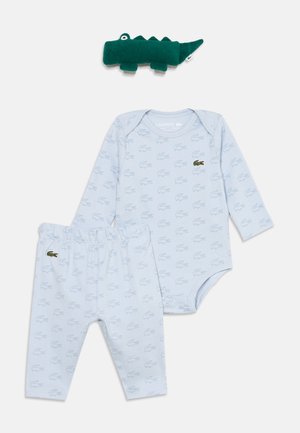 Lyseblåt babybody og bukser med små alligatorprint og grønne alligatorlogoer, sammen med en mørkegrøn plyskrokodille.
