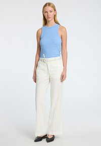 Modrá a bílá pruhovaná bezrukávová blůza v kombinaci s krémovými širokými kalhotami a černými balerínami. Lehký materiál s pohodlným střihem.