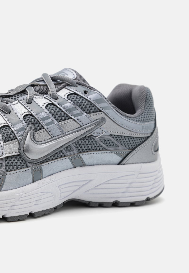 Grijze sportschoen gemaakt van mesh en synthetische materialen. Heeft een gestructureerd uiterlijk, een opvallend logo en een gevoerde, gestructureerde zool.