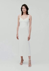 Vit ärmlös klänning med en figurnära bodice och rak kjol, med en subtil textur, längd till mitten av vaden, och öppna, snörkängor.