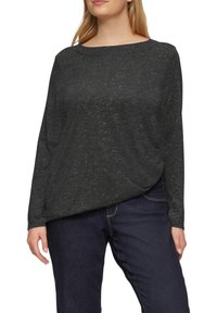 Zwarte longsleeve top met een losse pasvorm en bootcut halslijn; de textuur heeft een subtiel gemêleerd patroon. Gecombineerd met donkere spijkerbroeken.