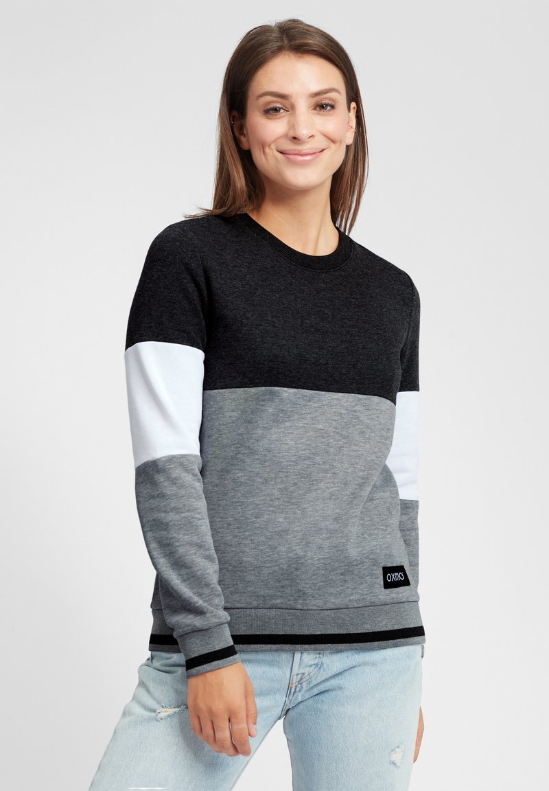 Crewneck sweatshirt i svart, grått og hvitt panel. Laget av myk stoff med ribbestrikket mansjetter og hem, med et logomerke nær bunnen.