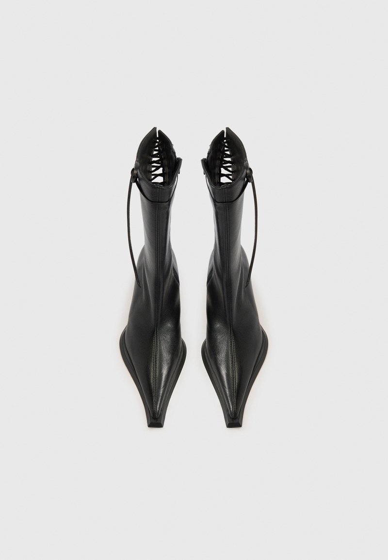 Schwarze Leder-Stiefeletten mit spitz zulaufender Zehenpartie, schlankem Design, offenem Fersenbereich und Schnürdetail am oberen Rand. Glatte Textur mit mattem Finish.