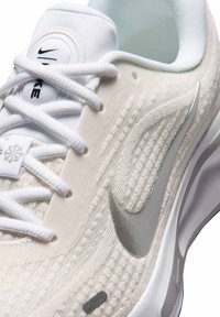 Close-up of white Nike running shoe with light texture, white laces, and silver Nike swoosh on side.