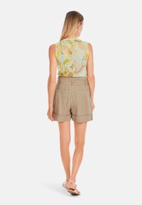 Sleeveless, pastel floral top with light green, yellow, and pink hues paired with tailored, khaki shorts featuring side pockets.