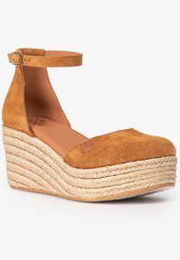 Sandalia de cuña de ante en color caramelo con tira en el tobillo, que presenta una plataforma de yute trenzado y un interior liso para mayor comodidad.