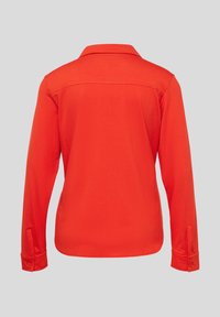 Red long-sleeve shirt with a collar, featuring a smooth texture and buttoned cuffs. Back view shows a simple, clean design without embellishments.