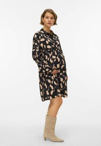 Czarna sukienka z liściastym beżowym wzorem, długimi rękawami i talią podkreśloną gumką. Do tego beżowe kozaki za kolano; gładka tekstura, casualowy styl.