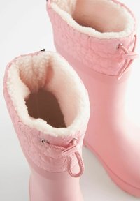 Botas de goma rosas con diseño floral texturizado, forro de felpa suave y cierre con cordón en la parte superior. Exterior suave con forma redondeada.