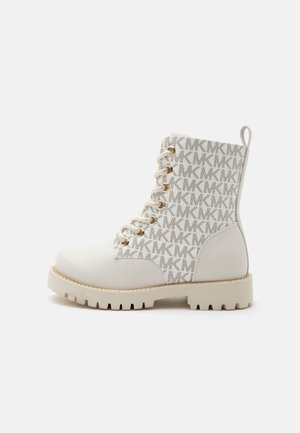 Botte de combat blanche avec semelle beige, œillets dorés, lacets beiges et dessus en tissu imprimé d'un motif répétitif du logo « MK ».