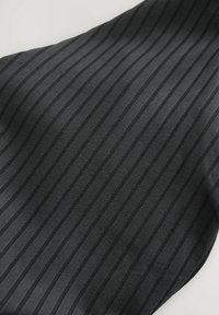 Juoda medžiaga su vertikaliu gipso raštu. Medžiagos paviršiuje kinta matinės ir blizgios juostos, kurios sudaro subtilų kontrastą.