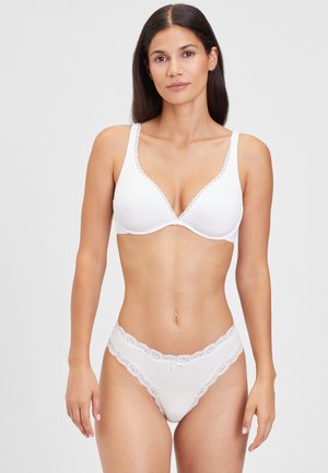 White lingerie set featuring a seamless bra with scalloped edges and lace detailing on the matching thong. Smooth fabric with a fitted design.