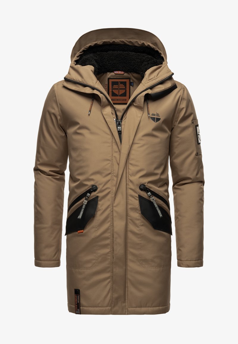 Bež parkas jakna z teksturirano kapuco, podloženo s flisom, črnimi žepi in zadrgami. Ima logotip na prsih in edinstvene pullerje na zadrgah.