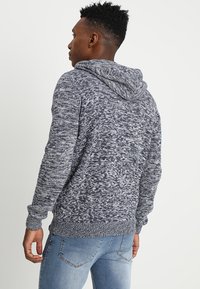 Hoodie in een marineblauwe en grijs gespikkelde brei. Heeft lange mouwen, ribgebreide boorden en zoom, en een standaard pasvorm.