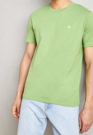 Hellgrünes T-Shirt mit kurzen Ärmeln aus Baumwolle. Verfügt über einen Rundhalsausschnitt und ein kleines weißes Logo auf der linken Brustseite. Weiche Textur.