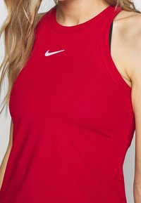 Débardeur de sport rouge en tissu respirant, avec un col rond et un petit logo Nike blanc sur le devant.